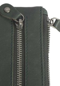Green leather wallet featuring a prominent silver zipper, contrasting stitching, and a snap closure at the top. Smooth texture and sleek design.