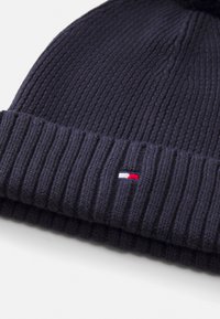 Meremeheline kootud beanie ribatekstuuriga ja voltitud äärega. Esipoolt kaunistab väike punane, valge ja sinine logo.