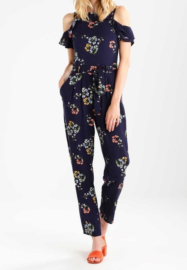 Navy floral jumpsuit with cold shoulder design, ruffled sleeves, belted waist, and straight legs. Features colorful, small floral patterns.
