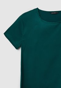 Top corto color teal realizzato in tessuto liscio. Presenta un colletto rotondo e cuciture pulite. L'etichetta riporta 'CALLIOPE' con la taglia 'S'.