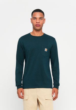 Long-sleeve, dark teal shirt made of cotton. Features a small chest pocket with a logo and relaxed fit. Textured fabric with a smooth finish.