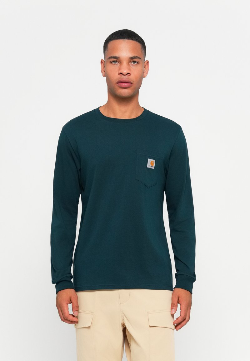 Lange mouwen, donkergroene shirt van katoen. Beschikt over een klein borstzakje met een logo en een ontspannen pasvorm. Gestructureerde stof met een gladde afwerking.