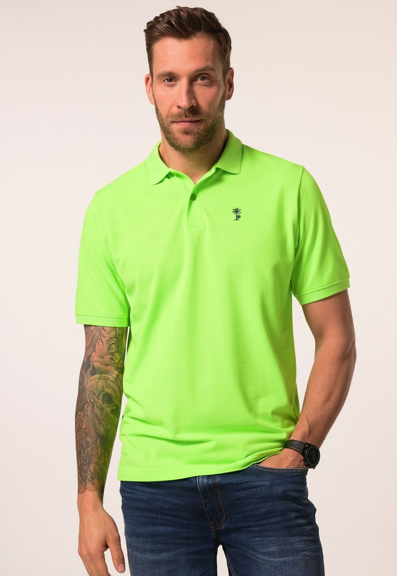 Neon zelené polo tričko s krátkými rukávy, s límečkem a malým logem palmy. V kombinaci s tmavě modrými džínami.