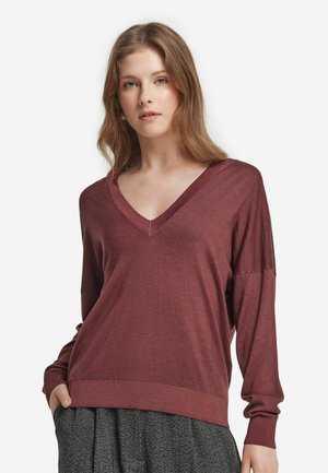 Pull en V bordeaux avec manches longues, poignets et ourlet côtelés, fabriqué en un tissu tricot doux, associé à une jupe grise texturée.