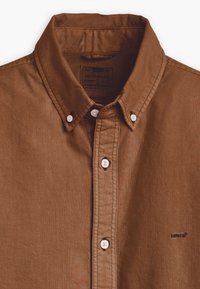 Brown button-up shirt made of textured fabric, featuring a classic collar, white buttons, and a Levi's logo embroidered on the chest.