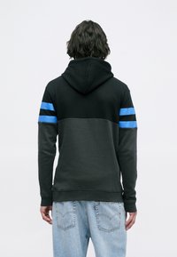 Sweatshirt com capuz em preto e cinza escuro, apresentando riscas azul e preta nas mangas, textura suave e punhos e bainha canelados.