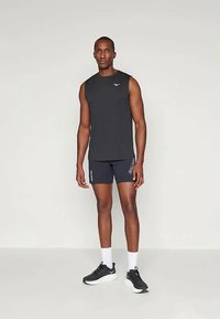 Top atlético preto sem mangas, calções azul-marinho com pormenores brancos e ténis pretos com solas brancas. Design simples e forma ajustada.