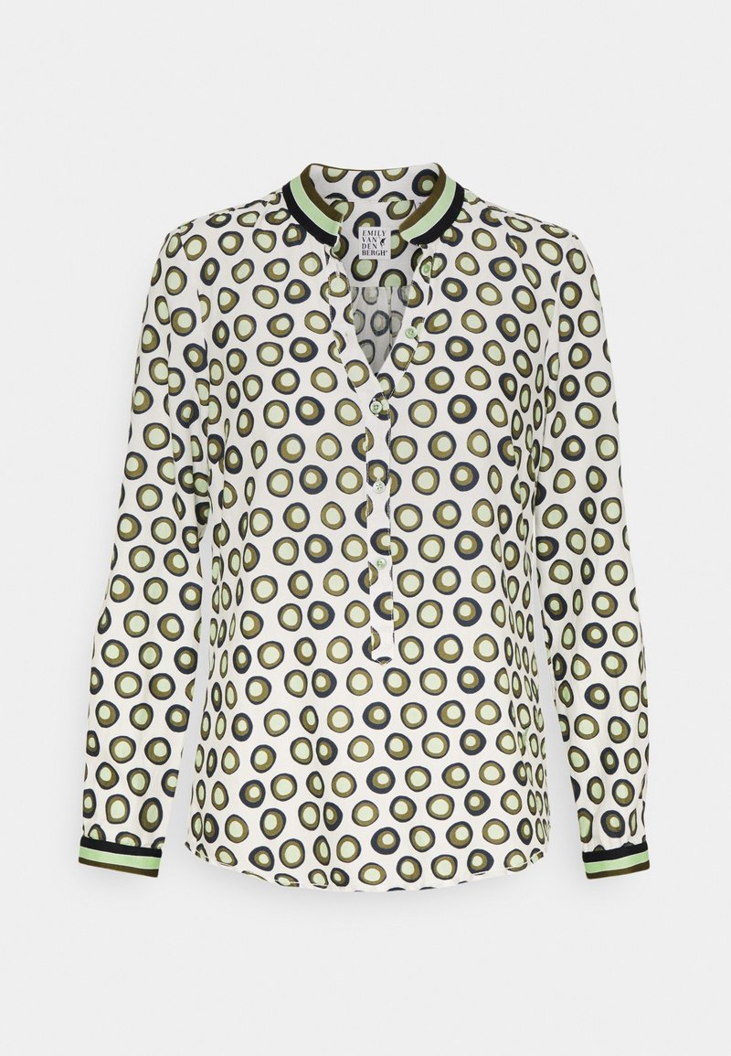 Blouse blanche à manches longues avec motif circulaire vert et noir, boutonnée sur le devant, col et poignets à rayures vertes et noires.