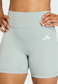 Shorts de sport bleu clair en matière extensible, avec une taille haute et un petit logo de marque blanc sur le côté.