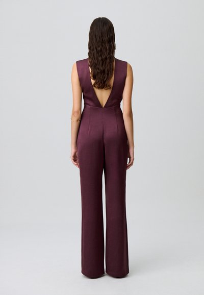 Mono burdeos con un profundo escote en la espalda, diseño sin mangas y silueta de pierna amplia. Fabricado con una tela suave y texturizada.