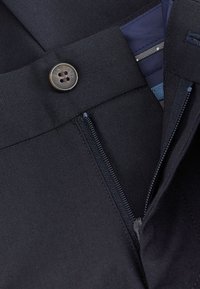 Czarne spodnie z tkaniny z zapięciem na guzik i suwak. Teksturowany materiał i ciemna podszewka wewnętrzna z subtelnym wzorem pasków.