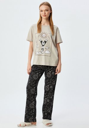 Light gray cotton t-shirt with a graphic design, paired with black pajama pants featuring white celestial patterns. Soft, comfortable fabric.