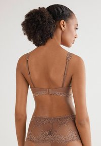 Brązowy stanik koronkowy z regulowanymi ramiączkami i ozdobnym koronkowym wykończeniem w kwiaty. Gładka tekstura z zapięciem na hak i oczko z tyłu.