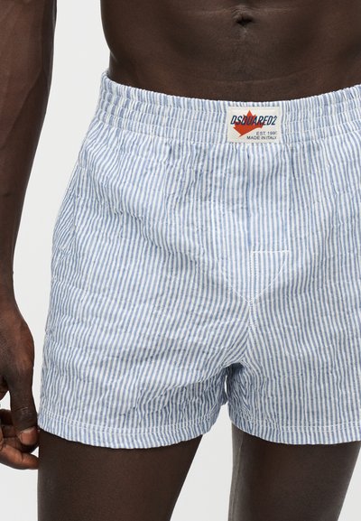 Torse masculin portant un boxer rayé vertical bleu clair et blanc avec ceinture élastique et patch logo Dsquared2.