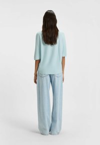 Top azzurro chiaro testurizzato con maniche corte, abbinato a jeans in denim chiaro dalla vestibilità morbida. Design semplice, silhouette rilassata, senza motivi visibili.