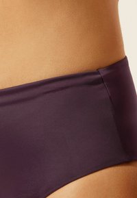 Lila Bikini-Unterteil aus einem glatten, elastischen Material mit breitem Bund und nahtlosen Seiten, entworfen für einen bequemen Sitz.