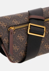 Smešasta smeđa torba preko tijela s uzorkom, koja ima zlatni zatvarač, crnu podesivu traku i smeđi kožni detalj s dizajnom loga.