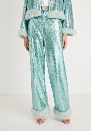 Completo a due pezzi in paillettes turchesi, con giacca corta con bordo in pelliccia e pantaloni a gamba larga con polsini in pelliccia coordinata.
