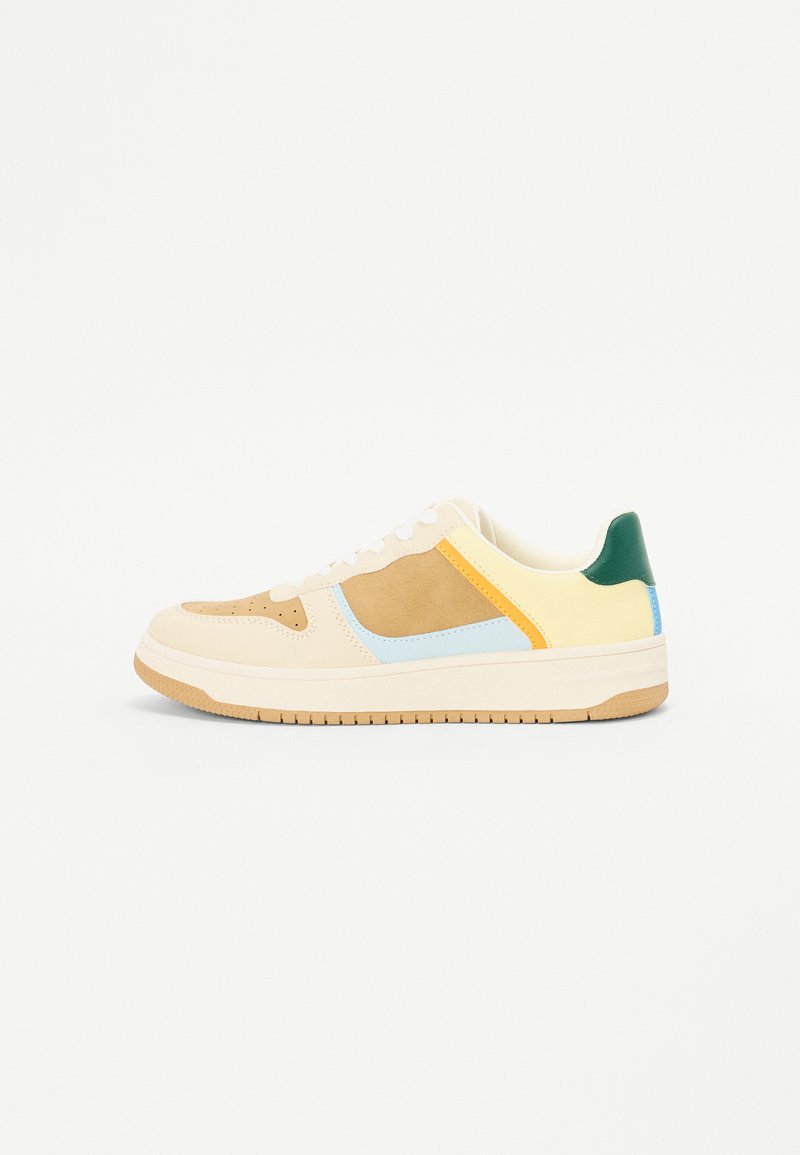 Sneakers with a beige leather and suede upper, featuring yellow, blue, and green accents. Flat rubber sole with a textured pattern.