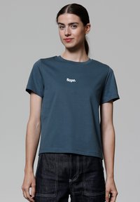 Türkisfarbiges Baumwoll-T-Shirt mit rundem Halsausschnitt, kurzen Ärmeln und weißem Text "Nein." auf der Brust. Glatte Textur.