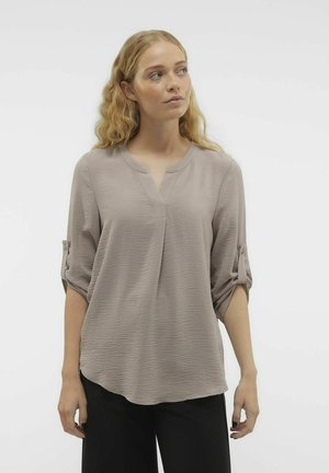 Heled taupe blouse V-kaelusega, kolmeveerandiste varrukatega, millel on rullitud Ääred ja tekstuuriga kangas. Lõtv lõige kaarja heljaga.