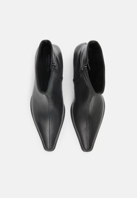 Stivaletti neri in pelle con punta affilata, cerniere laterali e texture liscia. Progettati con una silhouette elegante e minimalista.