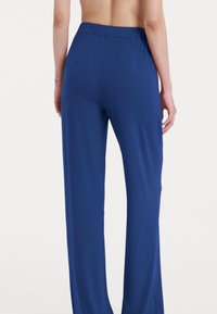 Pantaloni blu con vita elastica realizzati in un materiale morbido e liscio, caratterizzati da un design a gamba dritta e senza hardware o motivi visibili.