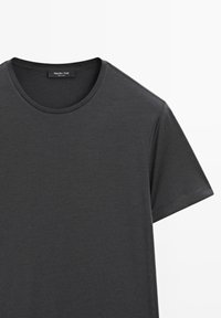 Mørkegrå bomulds T-shirt med rund hals og korte ærmer. Har en glat tekstur og minimalistisk design. Mærkets label er synlig.