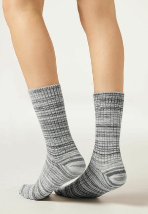 Chaussettes gris à côtes avec des teintes variées et des motifs rayés, dotées d'un large bord-côte et d'une texture lisse. Idéales pour un usage décontracté.