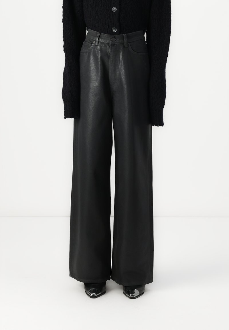 Black leather wide-leg trousers with a high waist, featuring front pockets and a smooth texture, paired with black heeled shoes.