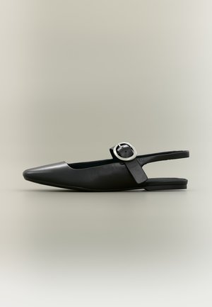 Chaussure plate slingback noire à bout pointu, boucle argentée et petit talon sur fond neutre.