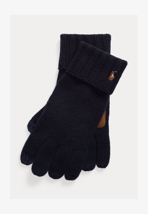 Nāvijas tumši zili adīti cimdi ar ribveida aprocēm, uz aproces ir brūna ādas detaļa un neliels izšūts logo.