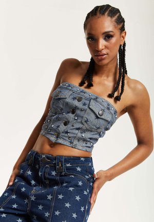 Denim strapless top with metallic stud details, two front pockets, and a cropped design. Paired with dark blue star-patterned jeans.
