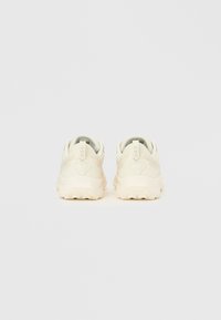 Μπεζ αθλητικά παπούτσια με υφασμάτινο επάνω μέρος με υφή, επενδεδυμένο περιλαίμιο και μαλακή σόλα, με διακριτική σήμανση στο πίσω μέρος.