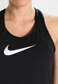 Schwarzes sportliches Tanktop aus glattem Material, mit einem weißen Nike Swoosh-Logo auf der Brust und einem klassischen Racerback-Design.