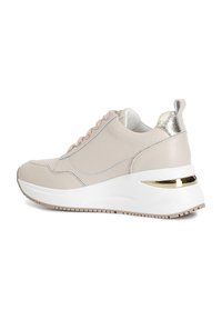 Vaaleanbeige nahkainen sneakeri, jossa on nauhakiinnitys edessä, metallinen yksityiskohta kantapäässä ja pehmeä valkoinen pohja. Kengissä on teksturoitu yksityiskohtaus ja tyylikäs muotoilu.