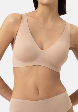 Nude seamless wireless bralette with a v-neck design, soft texture, wide straps, and minimalistic detailing on the band.
