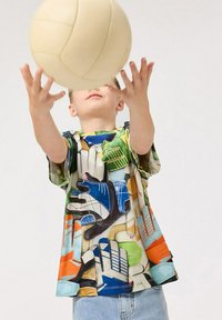 Väriä täynnä oleva lyhythihainen paita, jossa on leikkisä kuosi käsistä ja urheiluvälineistä sinisen, vihreän, oranssin ja beigekuvioiden sävyissä.