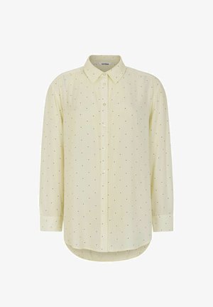 Kollane pika varrukaga särk, millel on nööbiga krae ja mustade punktide muster. Veidi ümar hem ja nööpide esiküljel sulgemine. Pehme kangatekstuur.