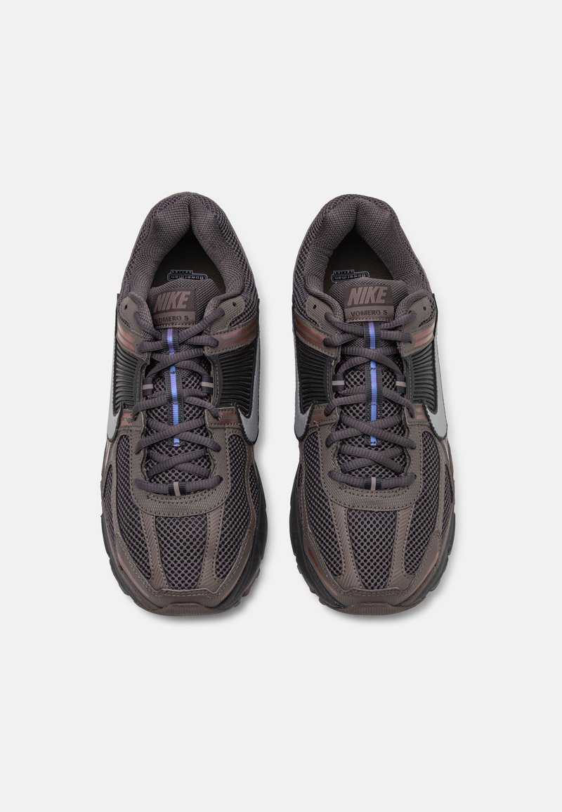 Nike Vomero 5 sneakers in donkergrijs mesh met zwarte accenten, paarse en blauwe veters, en een dikke zwarte rubberen zool.