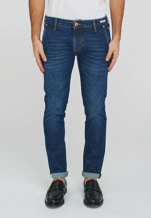 Jeans in denim blu scuro con vestibilità slim, cuciture a contrasto e orlo arrotolato. Presentano una chiusura con bottone e zip.