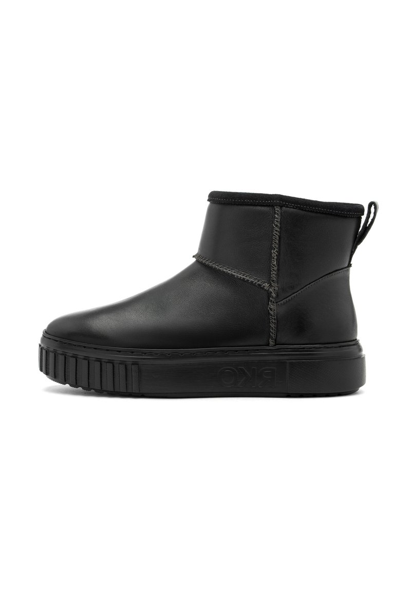 Botines de cuero negro con suela de goma estriada, punta redondeada y detalle de costura elástica. Presenta una cinta en la parte posterior para poner y quitar fácilmente.