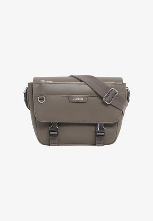 Graue Lacoste Crossbody-Tasche mit Frontklappe, silbernen Schnallenverschlüssen und verstellbarem Schulterriemen.
