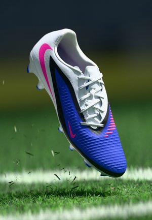 Nike voetbalschoen met een witte bovenkant met blauwe en zwarte accenten, een roze logo, een gestructureerd ontwerp en gemolde noppen voor grip.
