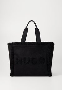 Czarna torba na ramię wykonana z miękkiej tkaniny z teksturowanym czarnym futrem. Z przodu haftowane logo "HUGO". Dwa solidne uchwyty na ramię.