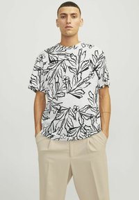 Kortærmet t-shirt med et sort blomstermønster på en hvid baggrund. Løs pasform med rund halsudskæring, lavet af letvægtsstof.