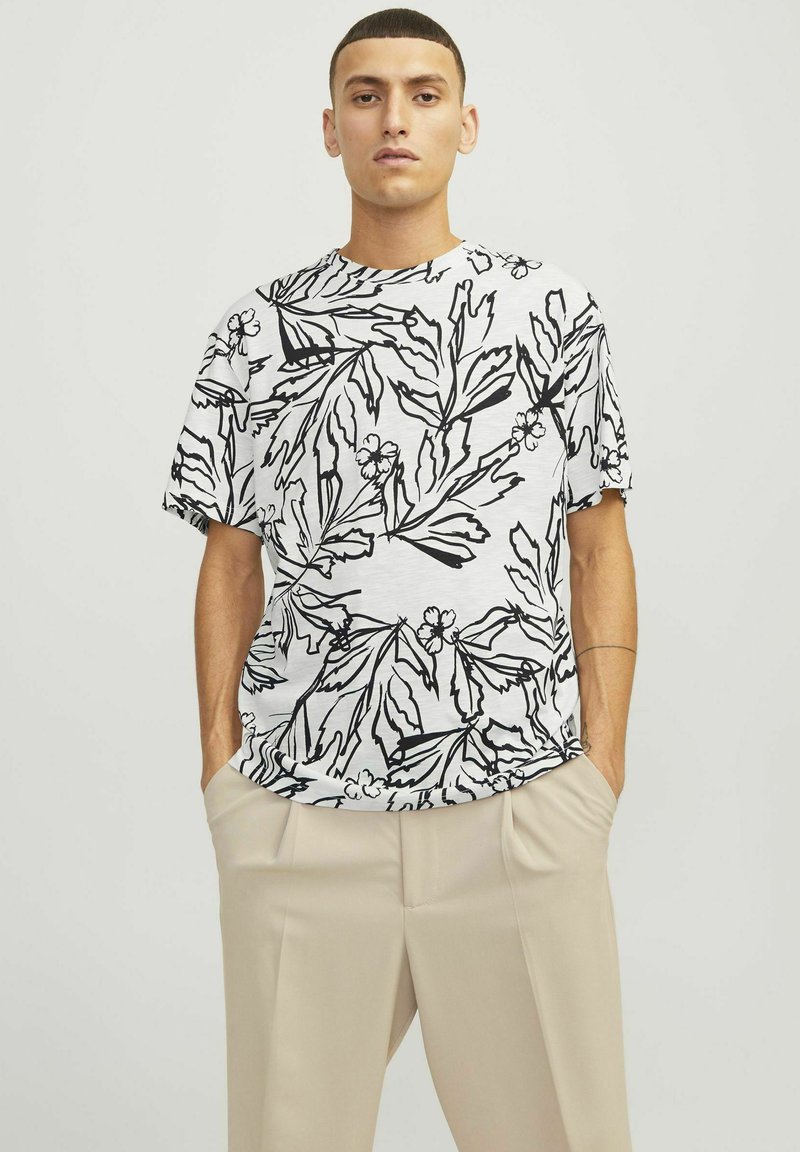 Kortærmet t-shirt med et sort blomstermønster på en hvid baggrund. Løs pasform med rund halsudskæring, lavet af letvægtsstof.