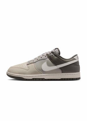 Baskets basses Nike beige, gris et blanc avec logo swoosh blanc et semelle grise, vues de côté sur fond blanc.