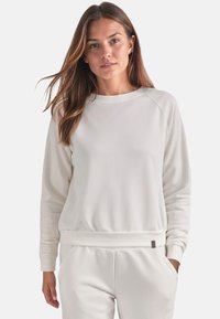 Witte sweatshirt met een ronde hals, ribgebreide manchetten en tailleband. De stof lijkt zacht met een gladde textuur. Beschikt over een klein logo-detail.