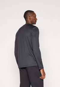 Schwarzes Langarmshirt aus einem glatten, leichten Stoff mit rundem Ausschnitt und lockerer Passform. Schlichtes Design, keine sichtbaren Muster oder Akzente.